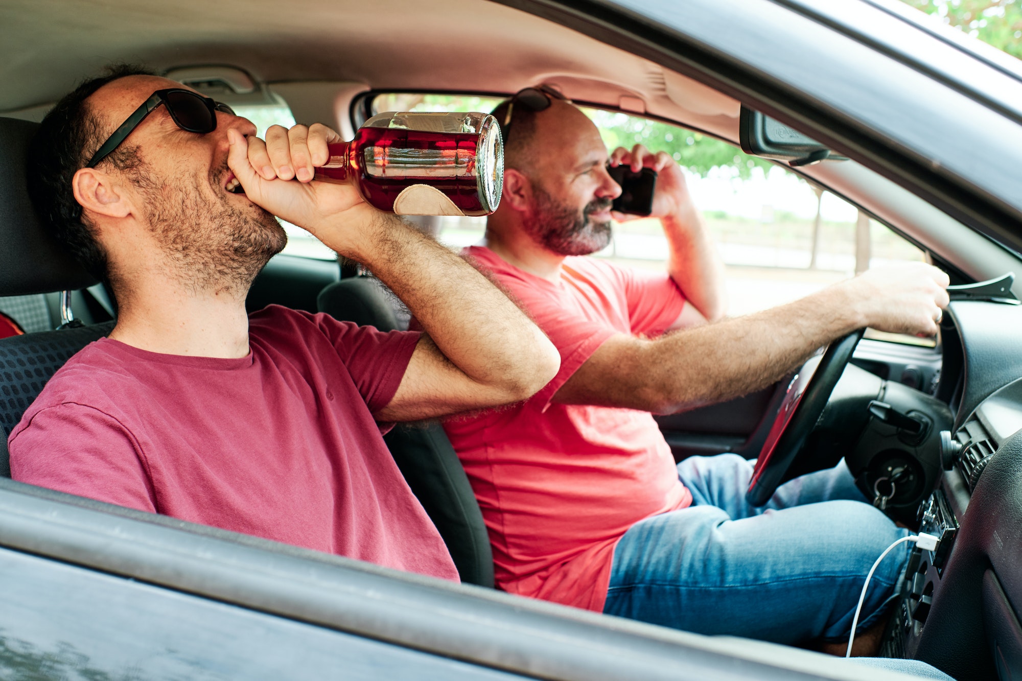 a man drinking and a driver using his mobile phone - alcoholism concept